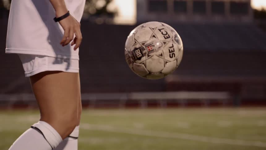 Soccer player tossing ball then kicking it with their feet while walking