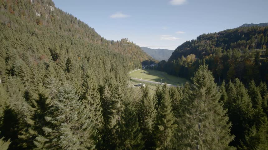 A large grassy clearing with a building in a mountain valley