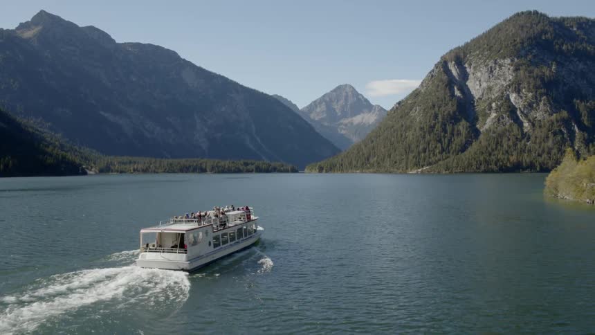 People on a leisure boat cruising on the lake through the mountains