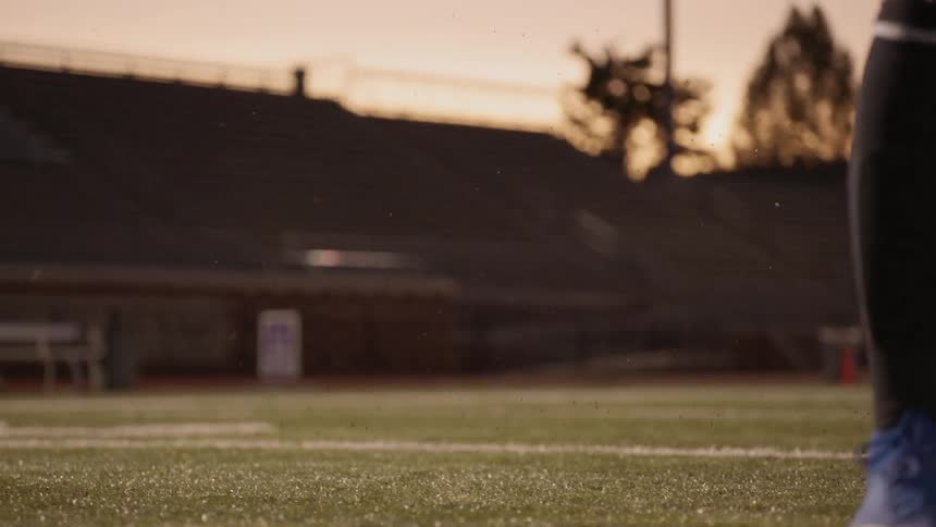 A soccer player kicks the ball at sunset