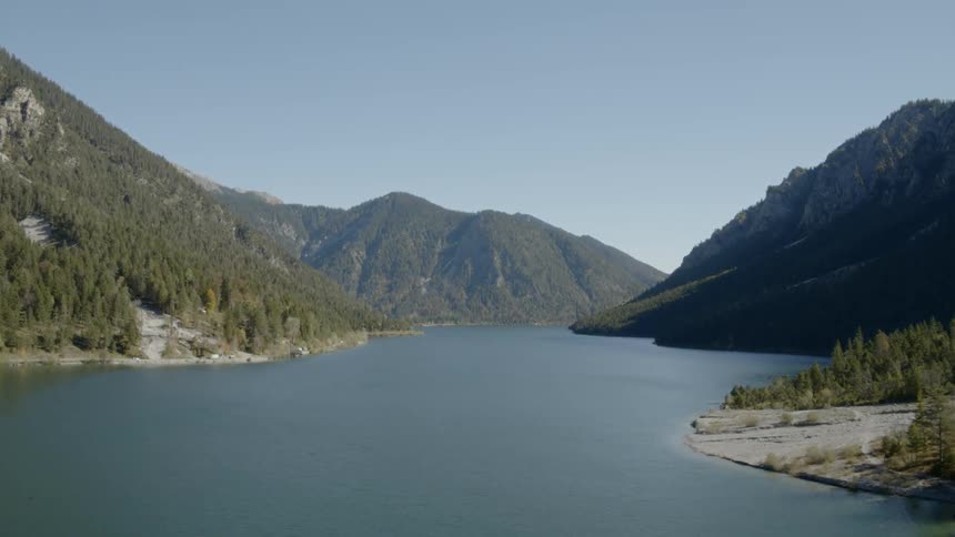 A lake is surrounded by forest covered mountains