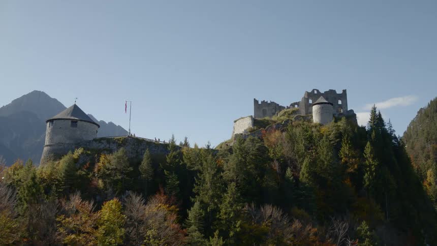 A castle sits on top of a large hill surrounded by trees