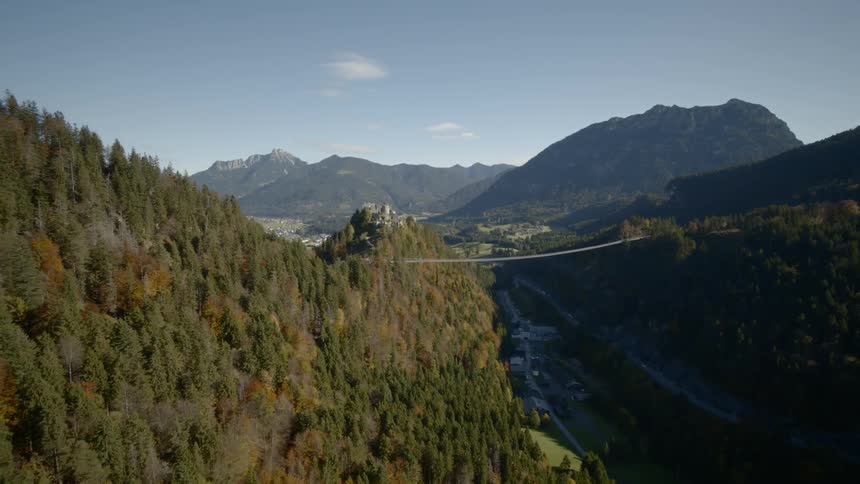 Two forest covered mountains with a suspension bridge connecting them