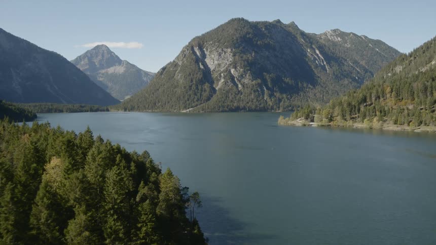 A reservoir is surrounded by forest covered mountains and hills