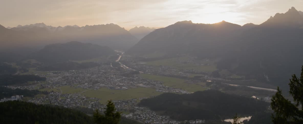 The sun rises over a mountain range near a neighborhood
