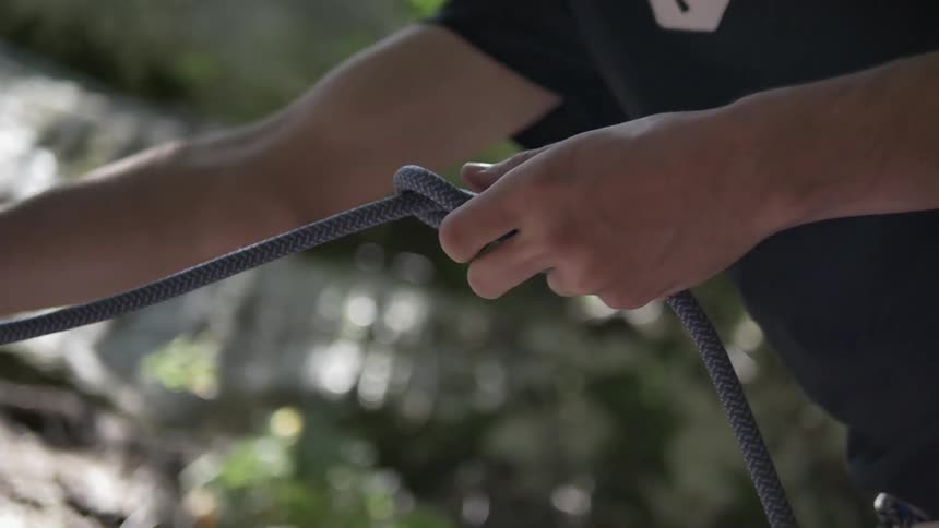 Person ties a knot in a length of rope outside