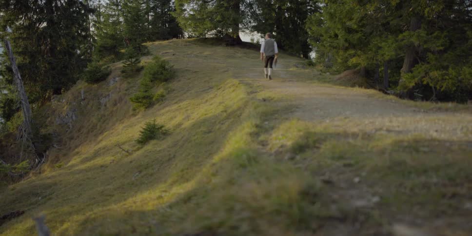 A man walking up a grass covered hill