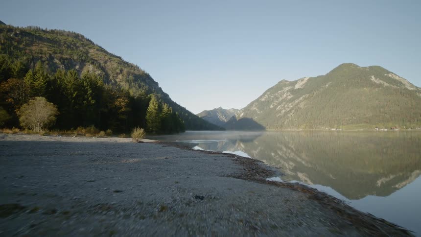 The camera flies along the shore of a mountain lake