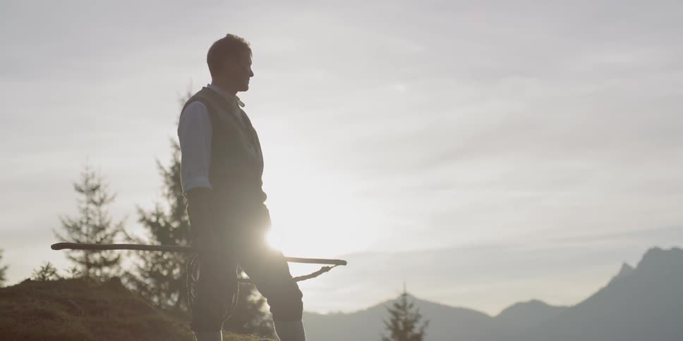 A man is looking around outdoors at dusk