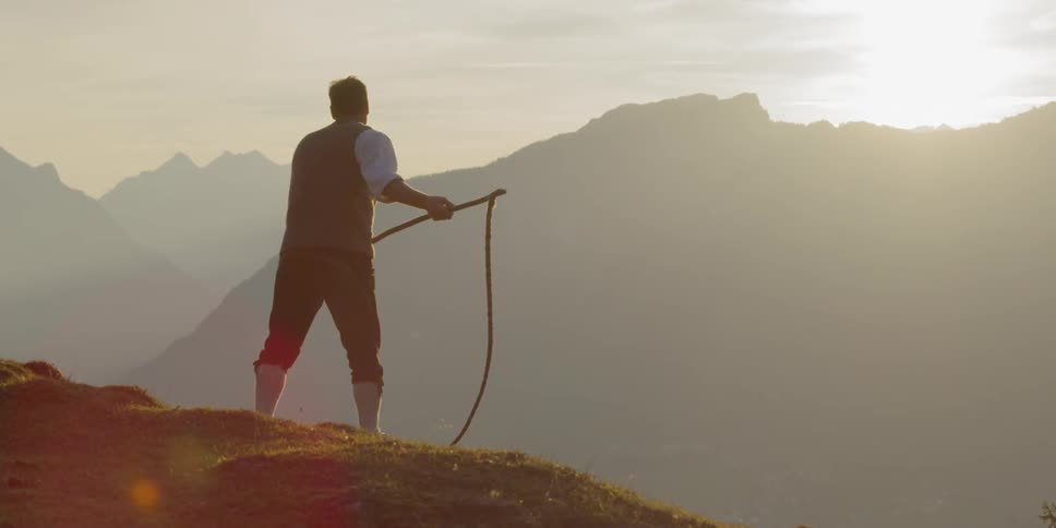 A man swings a whip on top of a mountain