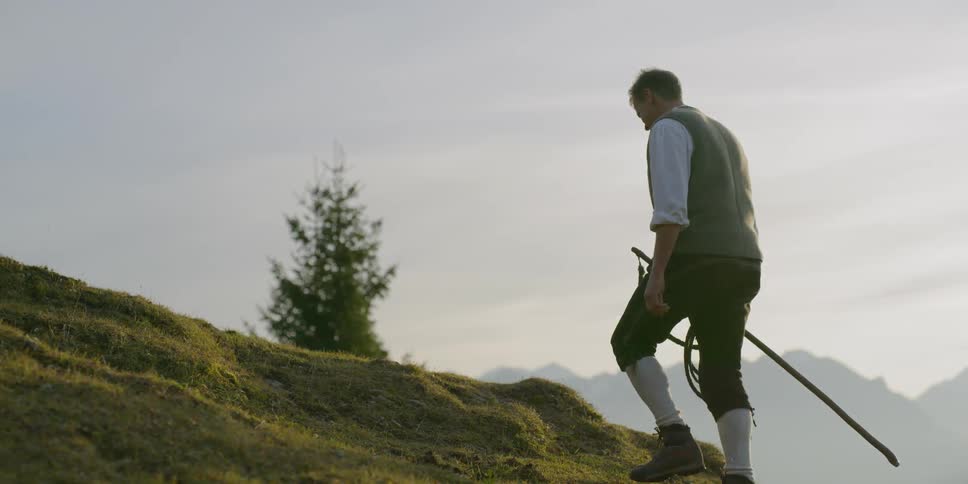 Man climbs slope carrying whip