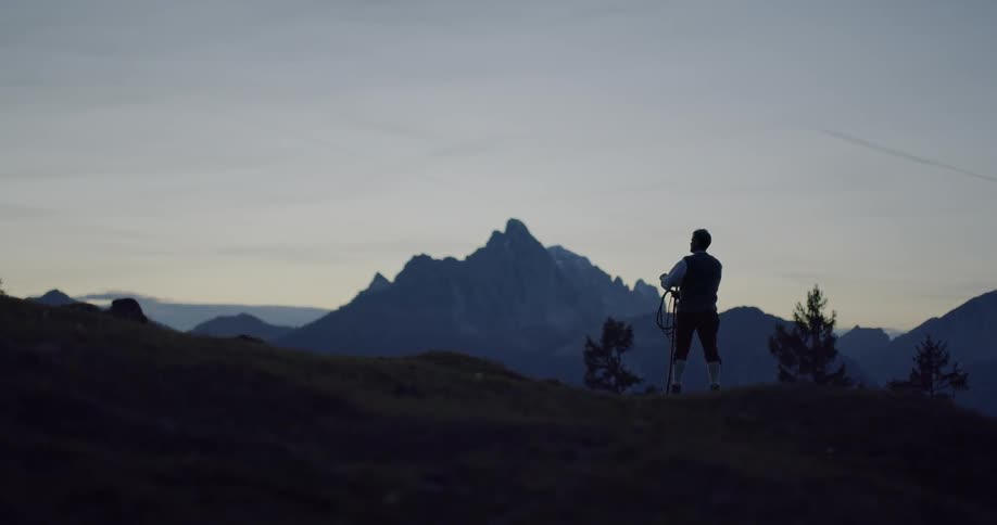 A man on a mountain holding a stick with a rope attached