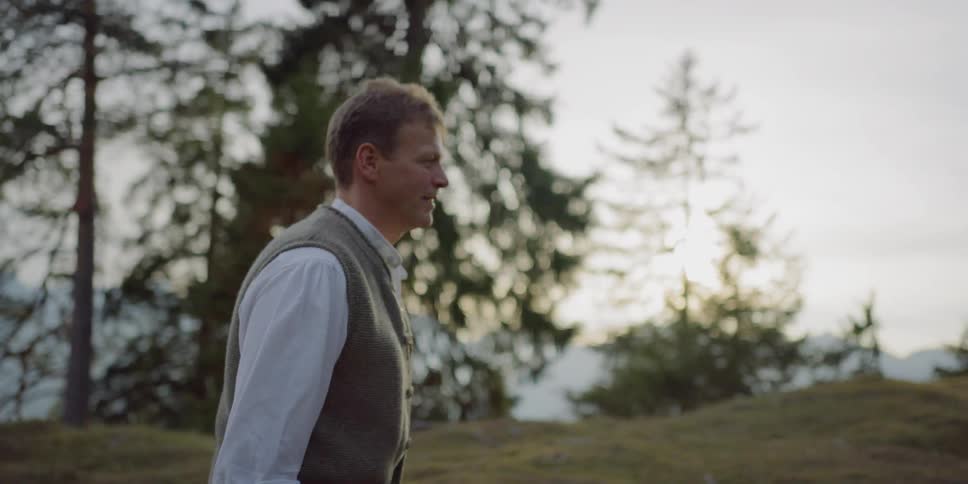A white man walks across a grassy field