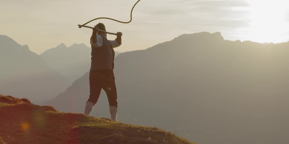 A man on a hill swings a whip around