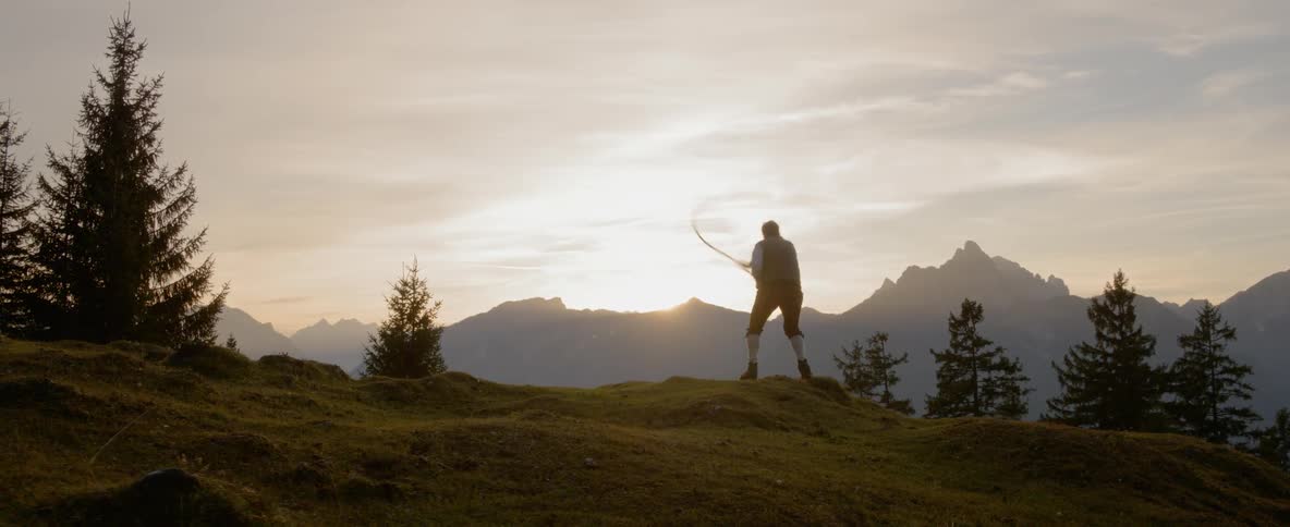A person swings a whip around on a hillside