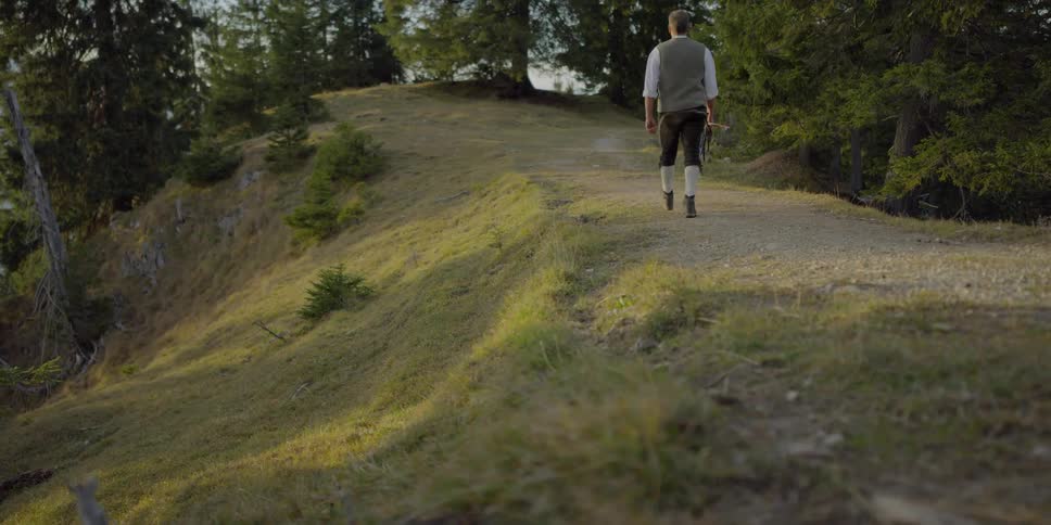 Man holding whip walks on the forest path at sunset