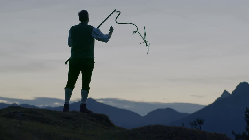 A man standing on a cliff throws a fishing line down