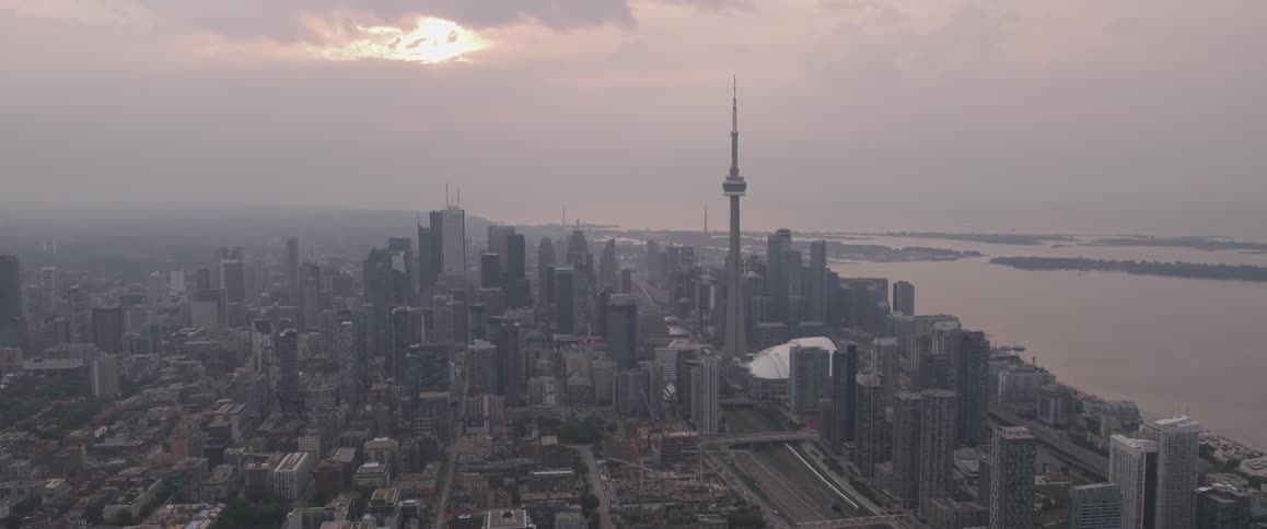 A city next to a body of water with a large tower on a cloudy day