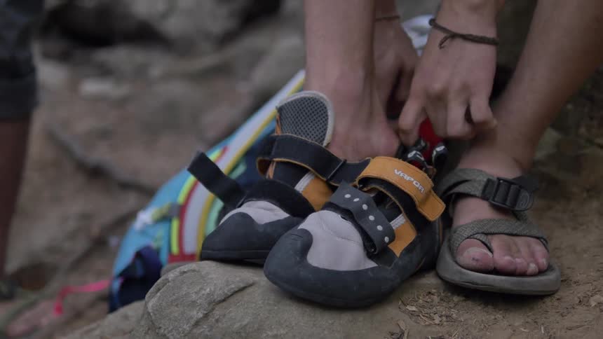 Person sitting on rocks putting on water shoes,