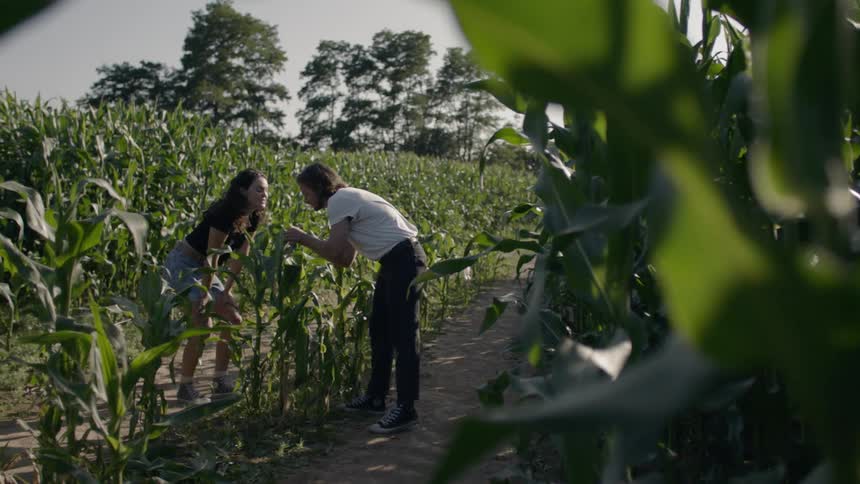A man and woman bend over looking at a plant