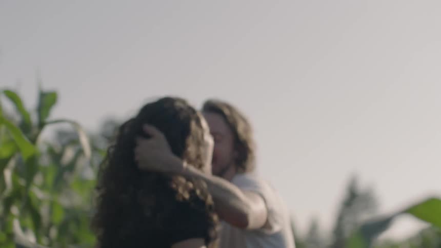 A couple hugs and plays in a corn field