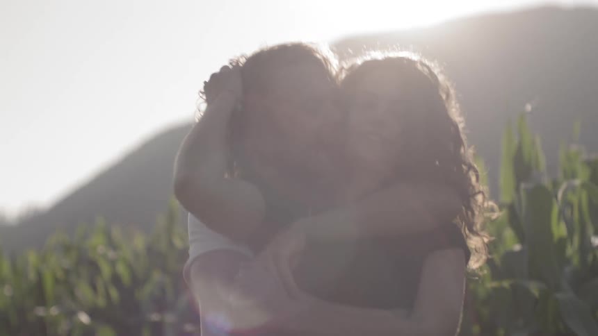A man and woman laugh and hug as they walk along