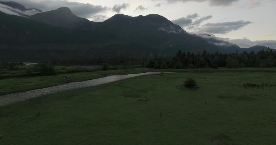 Aerial footage of a valley and river at base of mountain