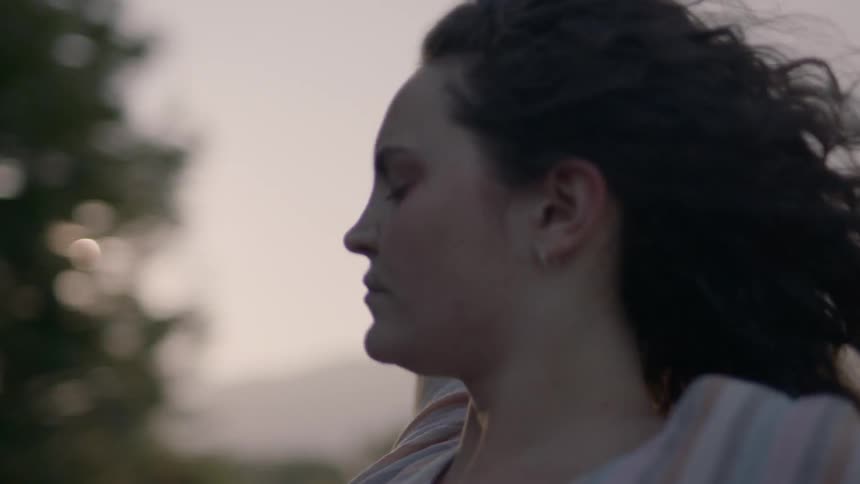 A white woman rides in a vehicle and holds her arms up to enjoy the wind