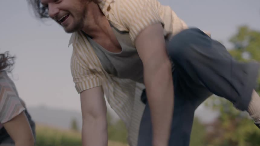 A young man and woman run and jump into the bed of a pick up truck breathing and laughing
