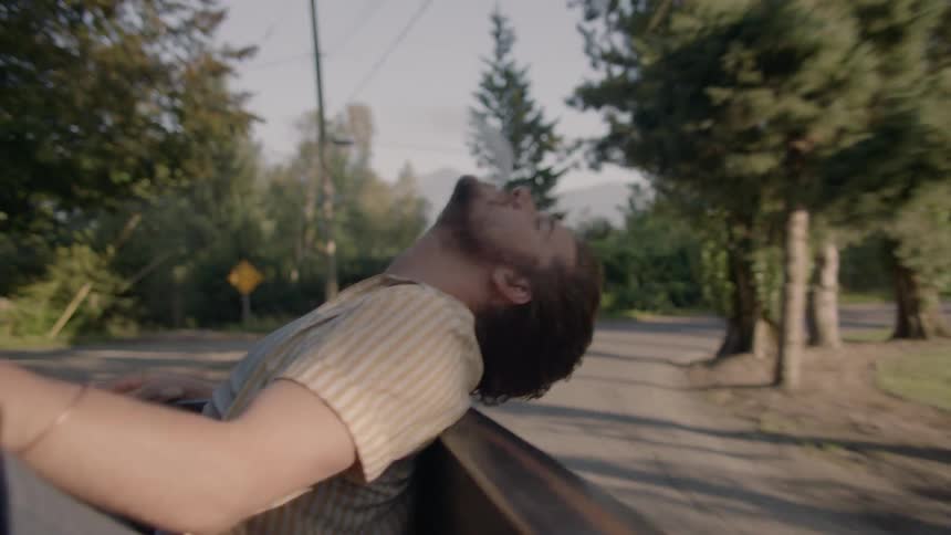 A man rides in the back of a truck smoking a cigarette