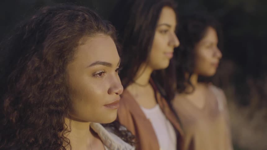 Three women stand side by side outdoors