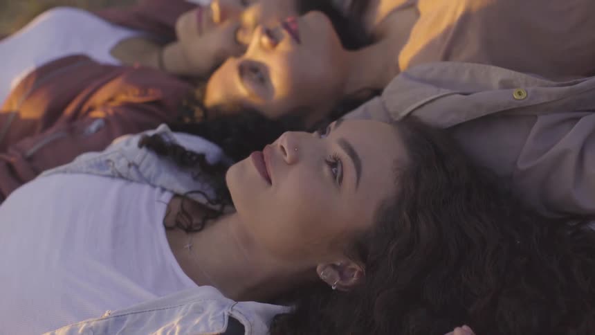 Three women laying outside looking at the sky