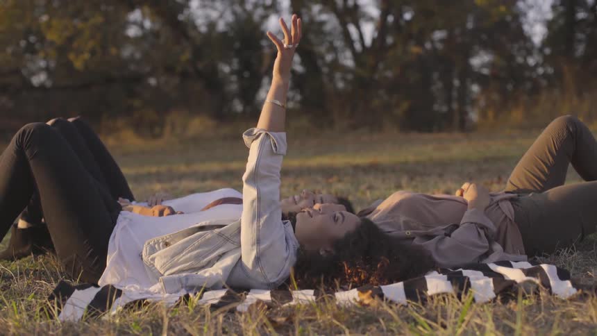 Three women laying on a blanket on the grass