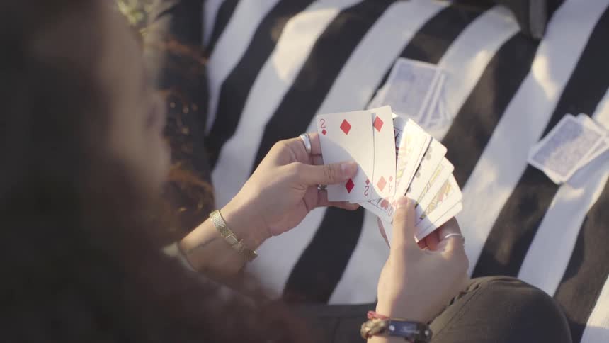 A young woman playing cards outside on a blanket