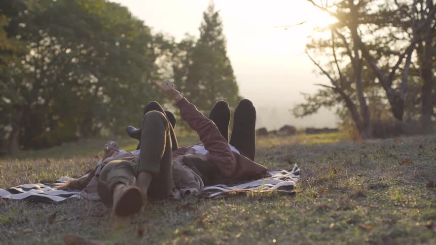 Three people lay on a blanket in the grass