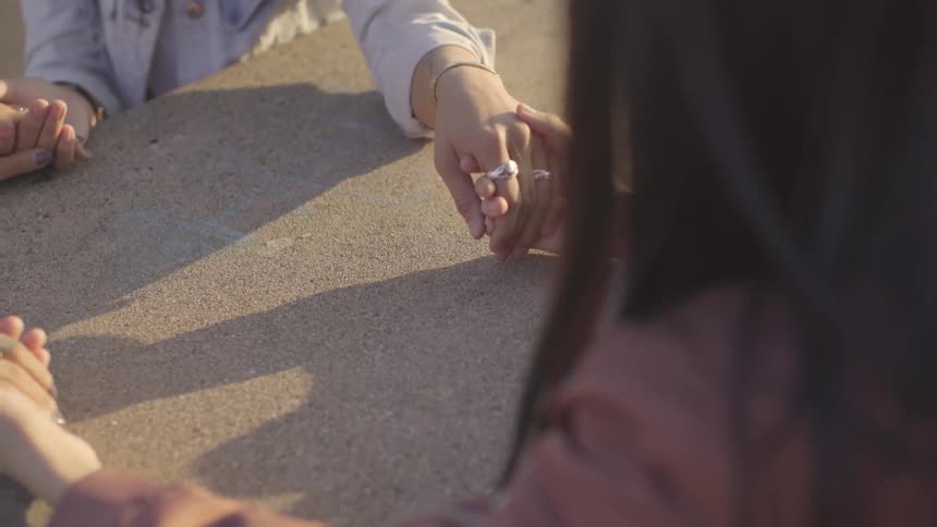Women sit outdoors and hold hands