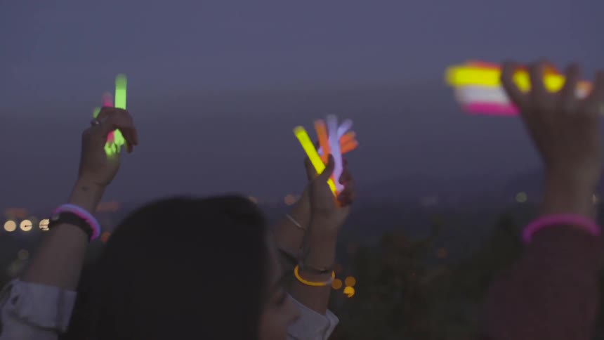 A group of women wave glow sticks in the air