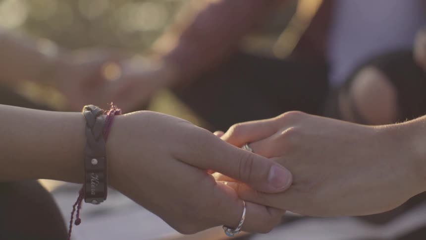 Women sit in a circle and hold hands