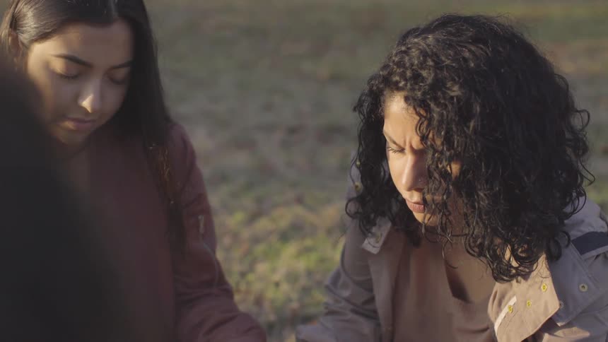 Women sit on the ground with their eyes closed