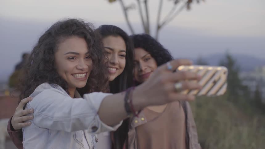 Three friends take a selfie on a hilltop