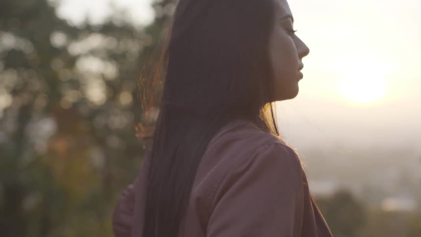 Woman stands outdoors finger combing her hair