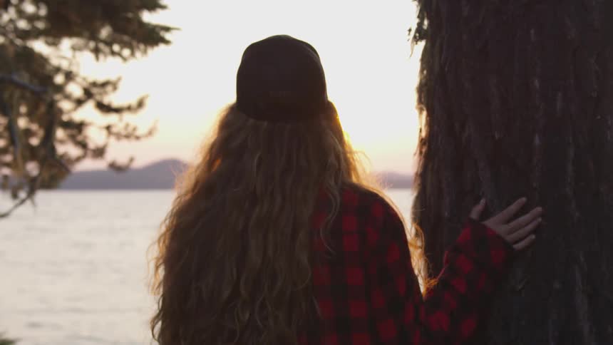 A woman is looking at the horizon at sunset