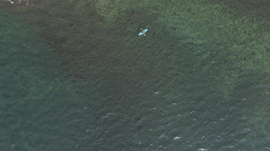 A canoeist paddling a canoe through a clear body of water