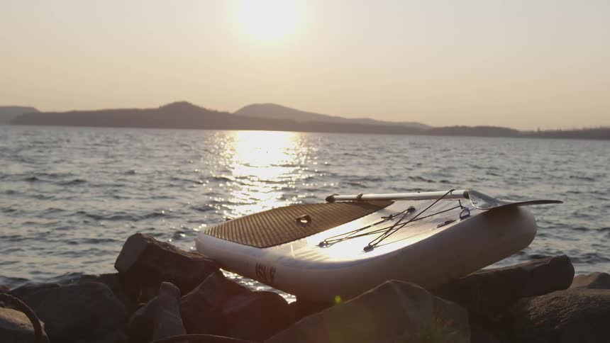 A row board is laying on the rocks by the shore