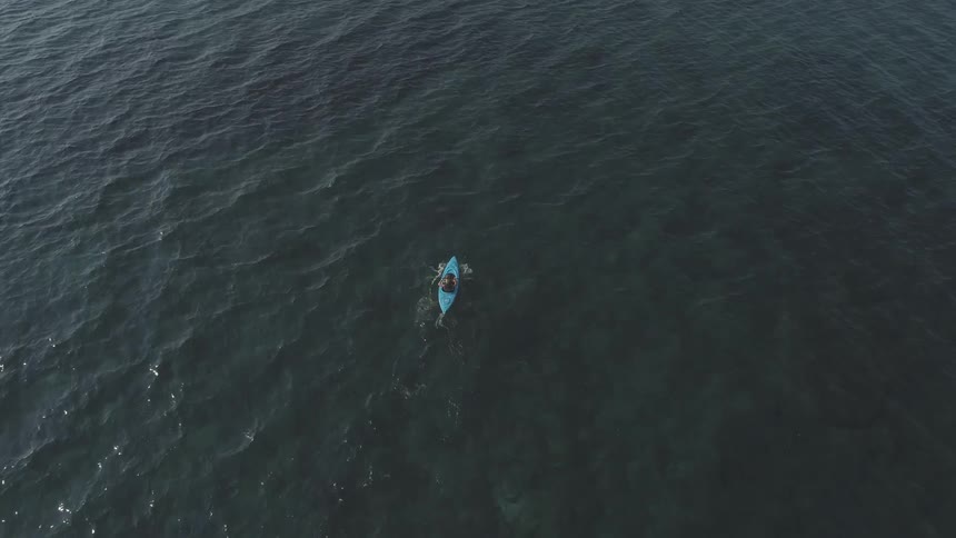 A person rows a kayak on a lake