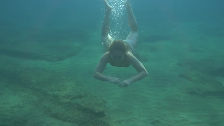 A woman dives into the water and starts to surface after swimming