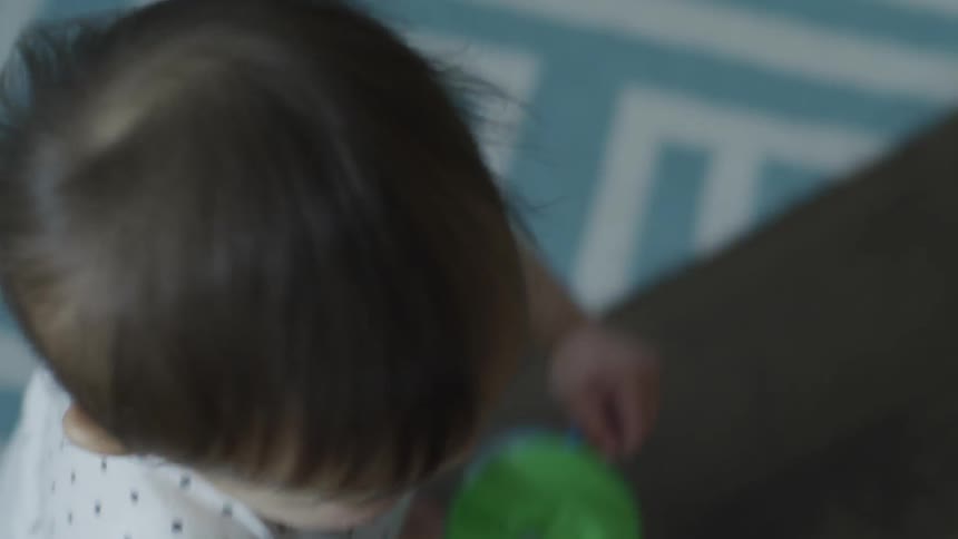 A toddler walks across a wooden floor