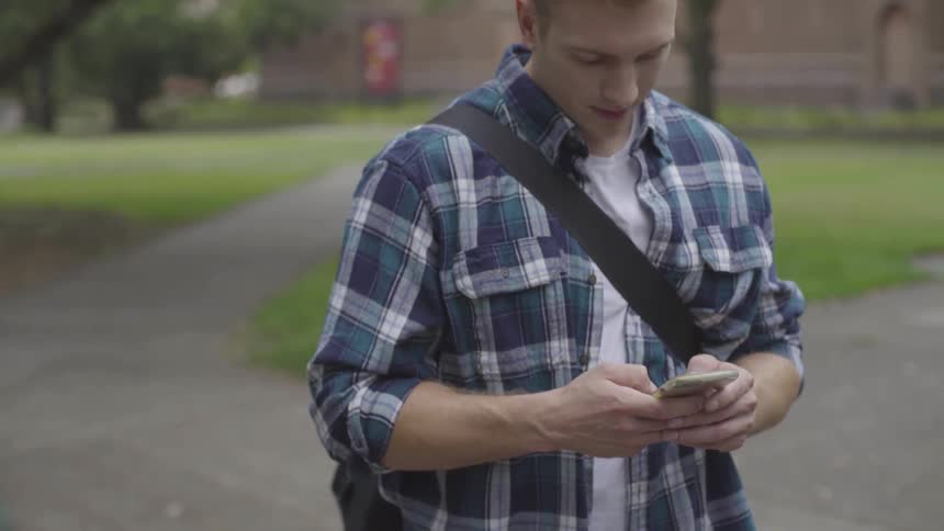 A man standing outside touching his smartphone