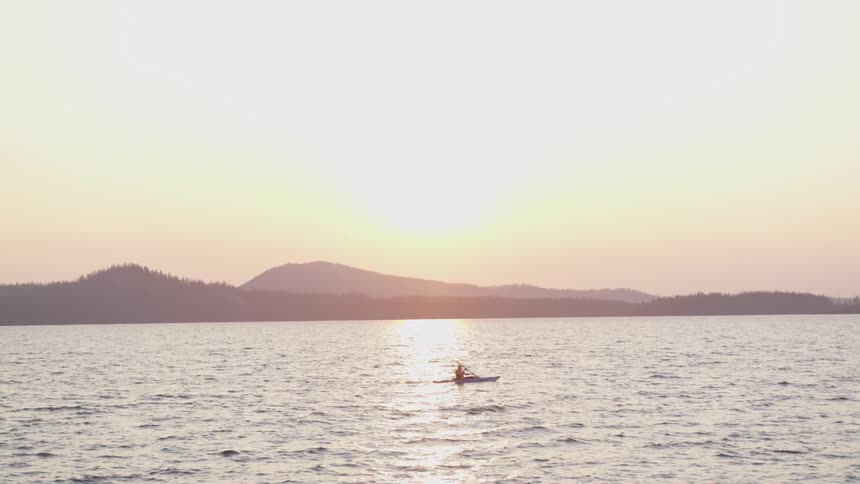A person canoeing on a lake in the evening