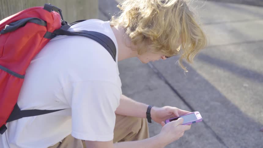 A man sits outside using his cell phone
